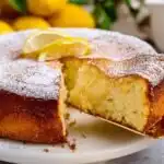High Protein Lemon Ricotta Cake – Soft and Moist 33 Whole high protein lemon ricotta cake dusted with powdered sugar on a white cake stand