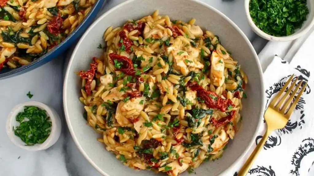 Mediterranean Chicken and Orzo 28 Mediterranean chicken and orzo with spinach and sundried tomatoes in a large skillet garnished with fresh parsley