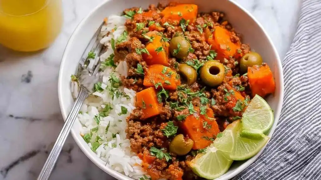 Mexican Picadillo 1 Overhead view of Mexican Picadillo in a cast iron skillet with ground beef, sweet potato, green olives, and a squeeze of lime