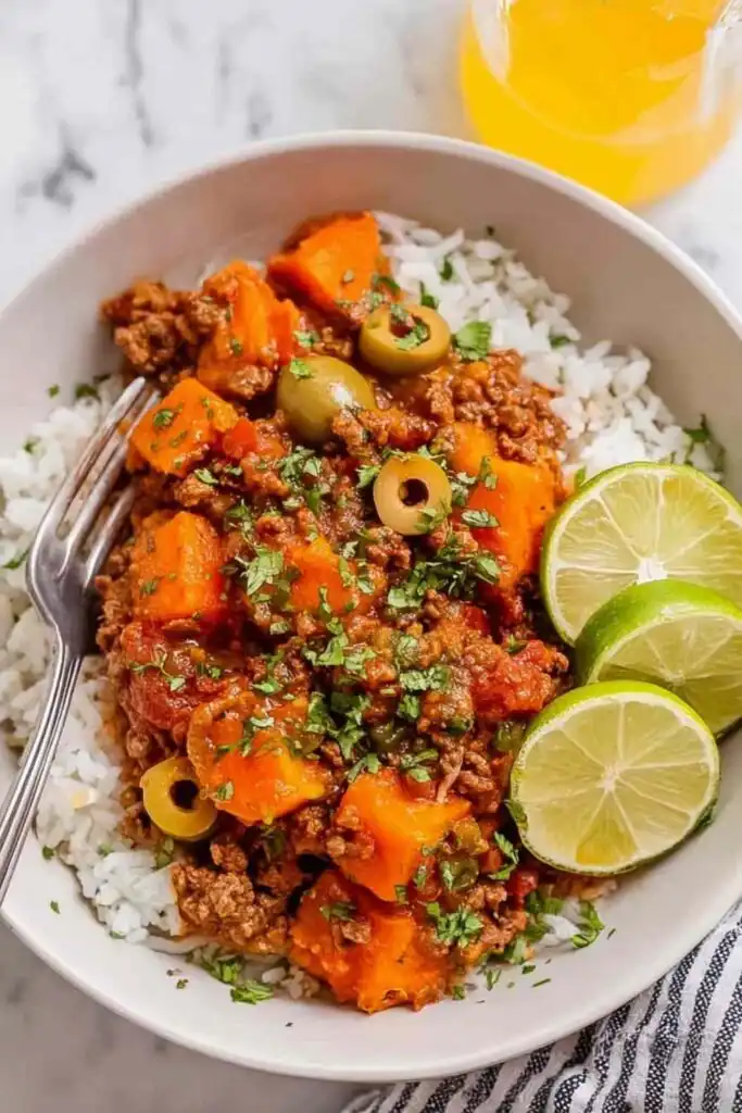 Mexican Picadillo 2 Overhead view of Mexican Picadillo in a cast iron skillet with ground beef, sweet potato, green olives, and a squeeze of lime