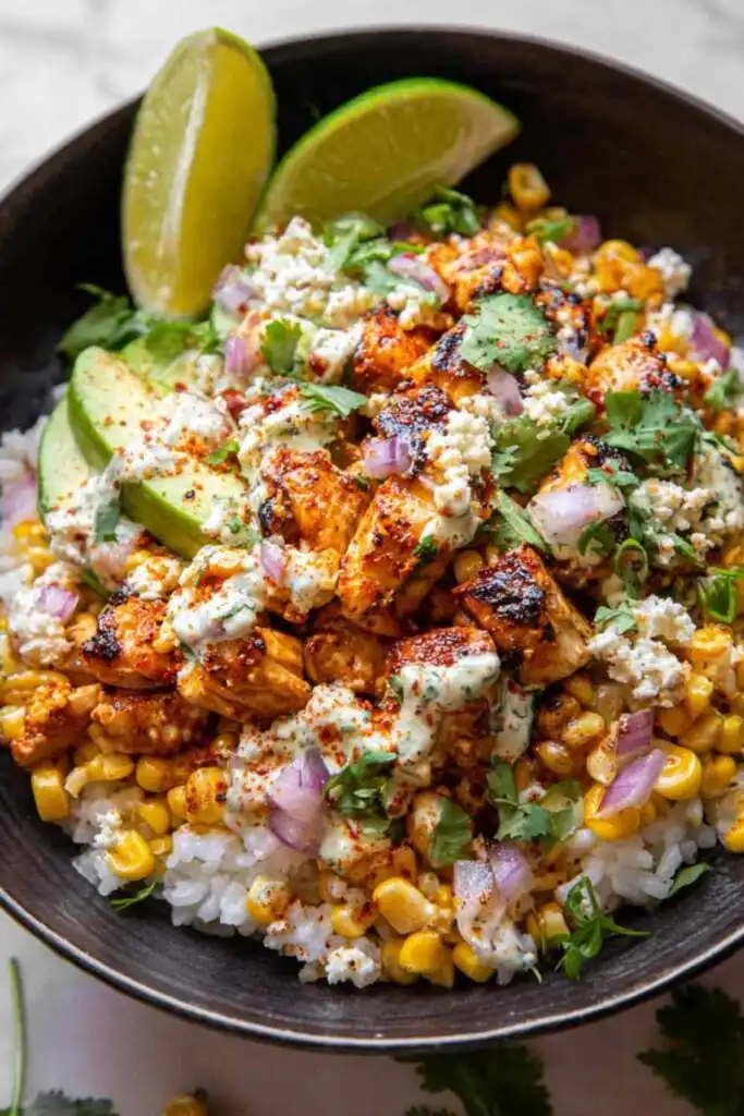 Street Corn Chicken Rice Bowl topped with creamy cotija lime street corn, sliced avocado, and smoky spiced chicken over white rice
