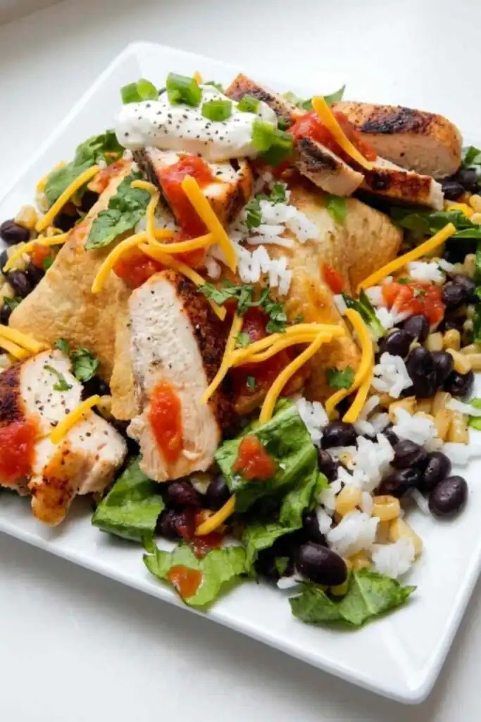Naked Chicken Burrito Bowl 17 Overhead view of a naked chicken burrito bowl with grilled chicken strips, black beans, corn, rice, sour cream, and chipotle salsa