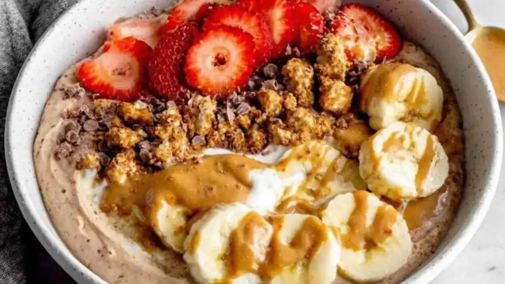 Chocolate Peanut Butter Protein Yogurt Bowl 10 Chocolate peanut butter protein yogurt bowl topped with granola and fresh strawberries in a white bowl