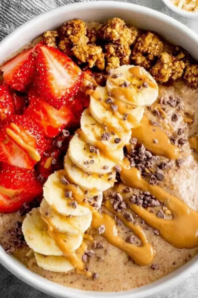 Chocolate Peanut Butter Protein Yogurt Bowl 11 Chocolate peanut butter protein yogurt bowl topped with granola and fresh strawberries in a white bowl
