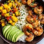 Shrimp and Avocado Bowls with Mango Salsa and Lime-Chili Sauce served over rice, viewed from above with cilantro garnish
