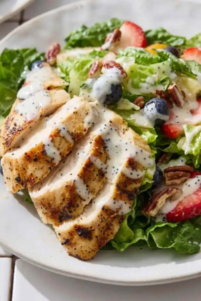Copycat Panera Strawberry Poppyseed Chicken Salad 14 Copycat Panera Strawberry Poppyseed Chicken Salad on a white plate with sliced grilled chicken, fresh strawberries, blueberries, toasted pecans, and creamy poppy seed dressing