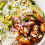 Overhead view of a street corn chicken rice bowl with spiced chicken, creamy corn salad, avocado, cotija cheese, and cilantro on cilantro lime rice