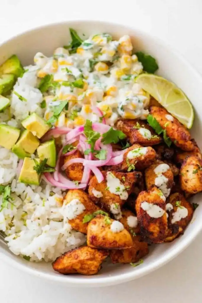 Overhead view of a street corn chicken rice bowl with spiced chicken, creamy corn salad, avocado, cotija cheese, and cilantro on cilantro lime rice