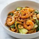 Szechuan Noodles with Garlic Shrimp 6 Szechuan Noodles with Garlic Shrimp in a skillet topped with toasted sesame seeds and homemade garlic chili oil