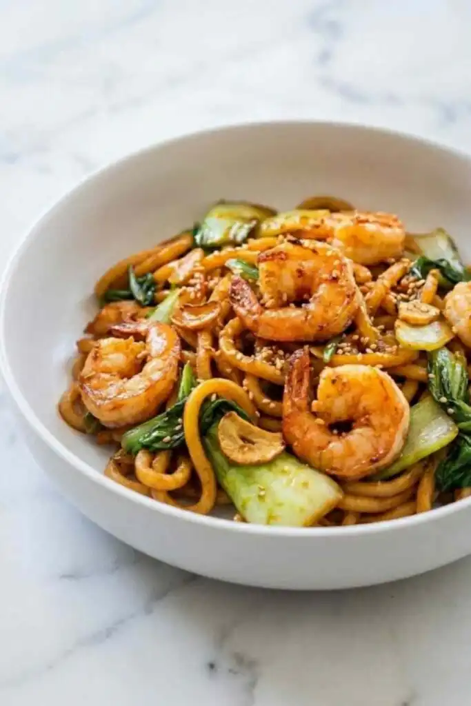 Szechuan Noodles with Garlic Shrimp 5 Szechuan Noodles with Garlic Shrimp in a skillet topped with toasted sesame seeds and homemade garlic chili oil