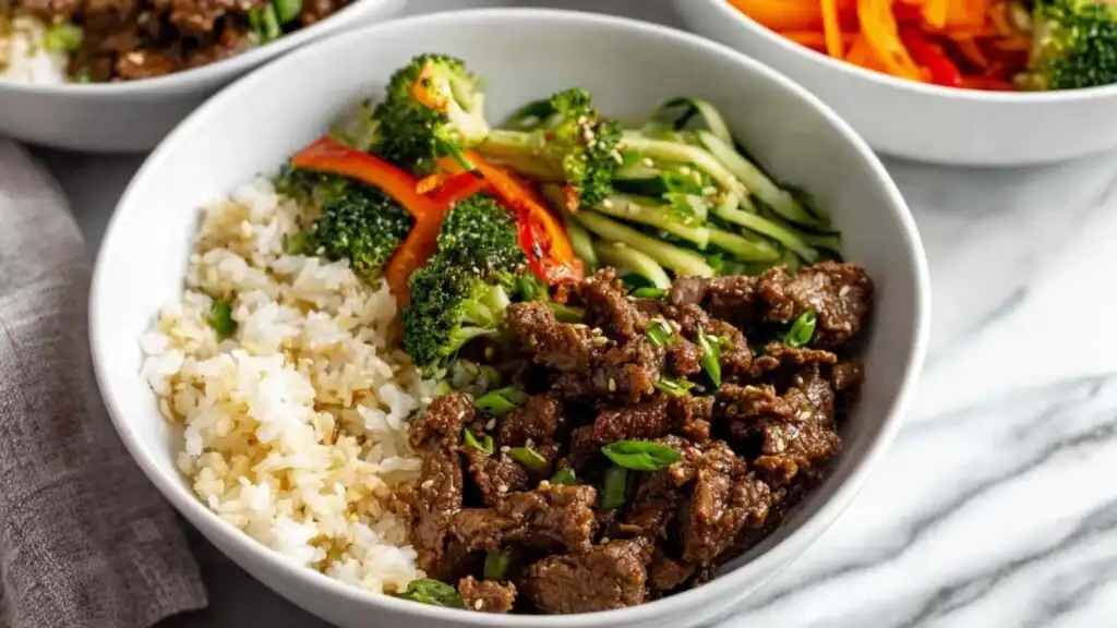 Teriyaki Beef Bowls 16 Overhead view of a high protein teriyaki beef bowl with seasoned ground beef, broccoli, bell peppers, carrots, and cauliflower jasmine rice blend topped with green onions
