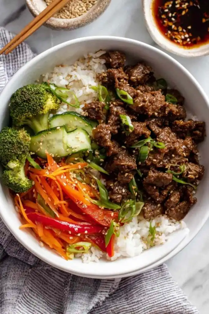 Teriyaki Beef Bowls 17 Overhead view of a high protein teriyaki beef bowl with seasoned ground beef, broccoli, bell peppers, carrots, and cauliflower jasmine rice blend topped with green onions